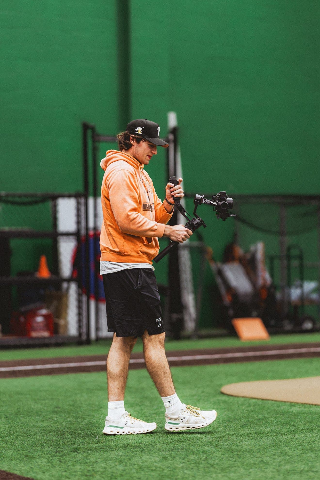 Liam Besecker walking across indoor turf with a camera on a gimbal rig