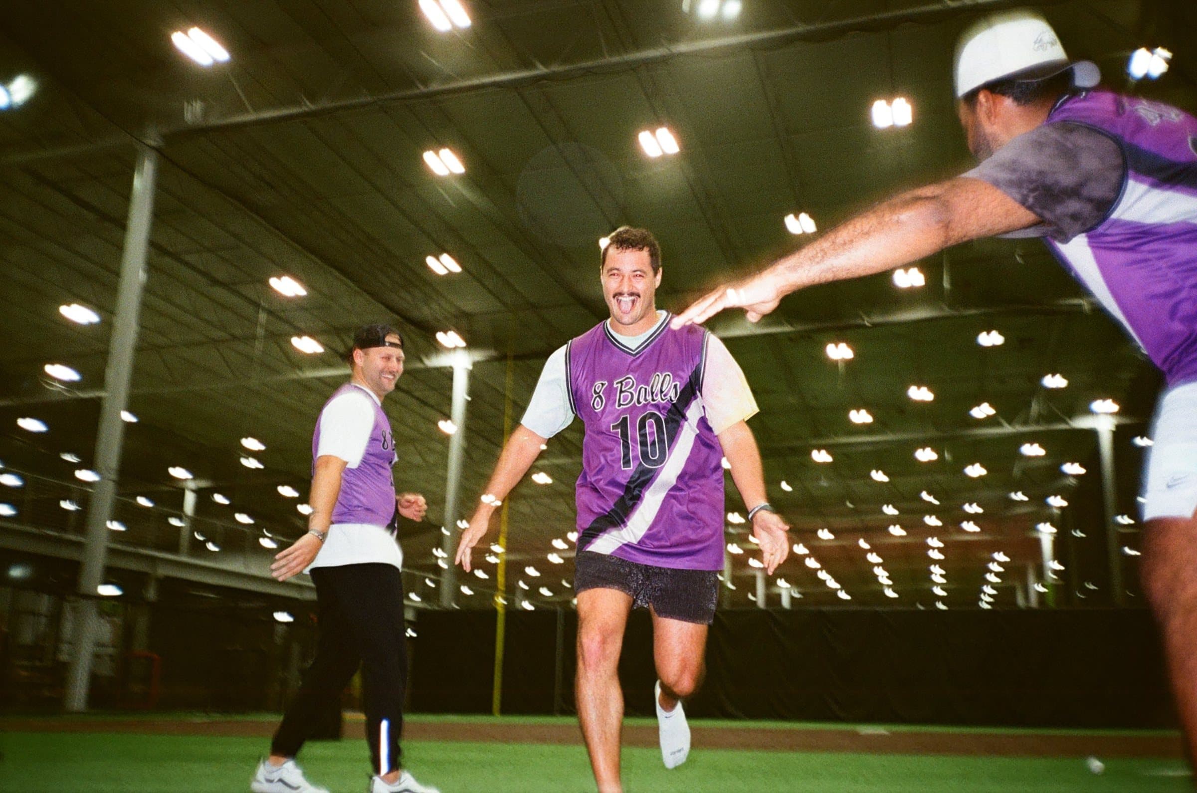 Player in a purple 8 Balls number 10 jersey celebrating inside an indoor turf dome