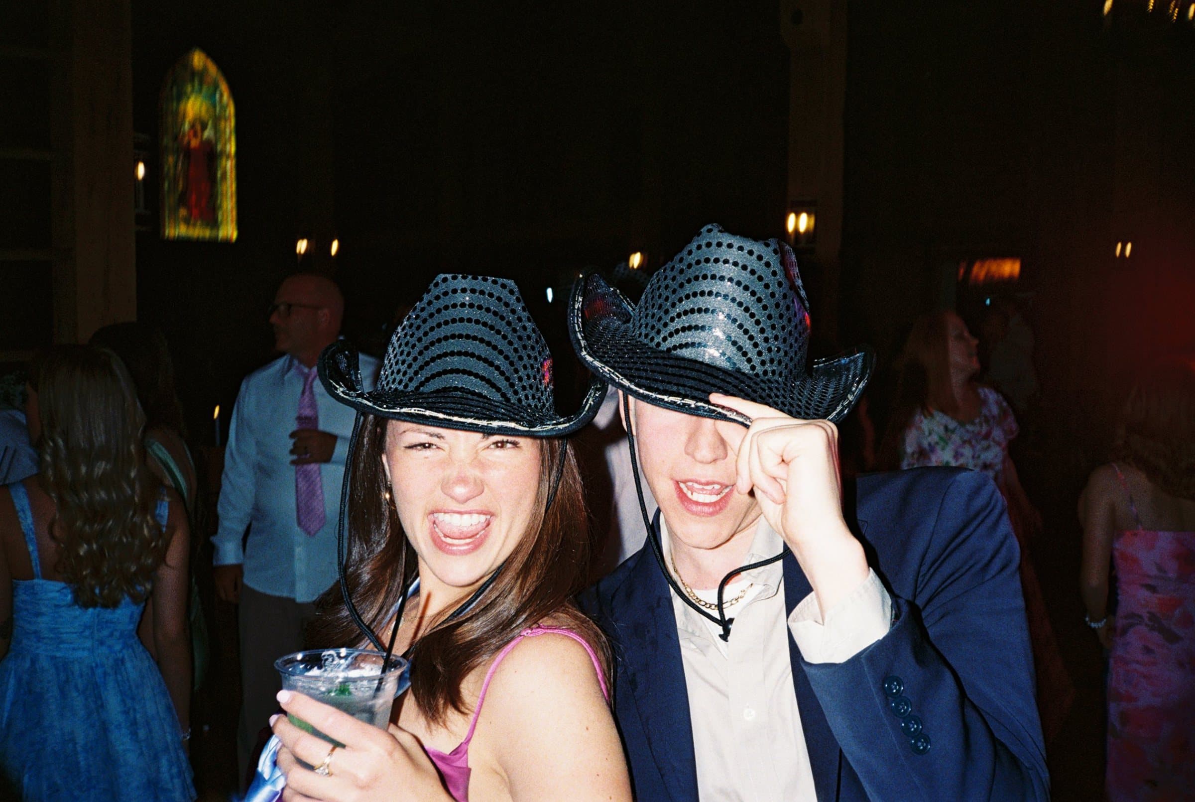 Two friends in sequined cowboy hats laughing at a party