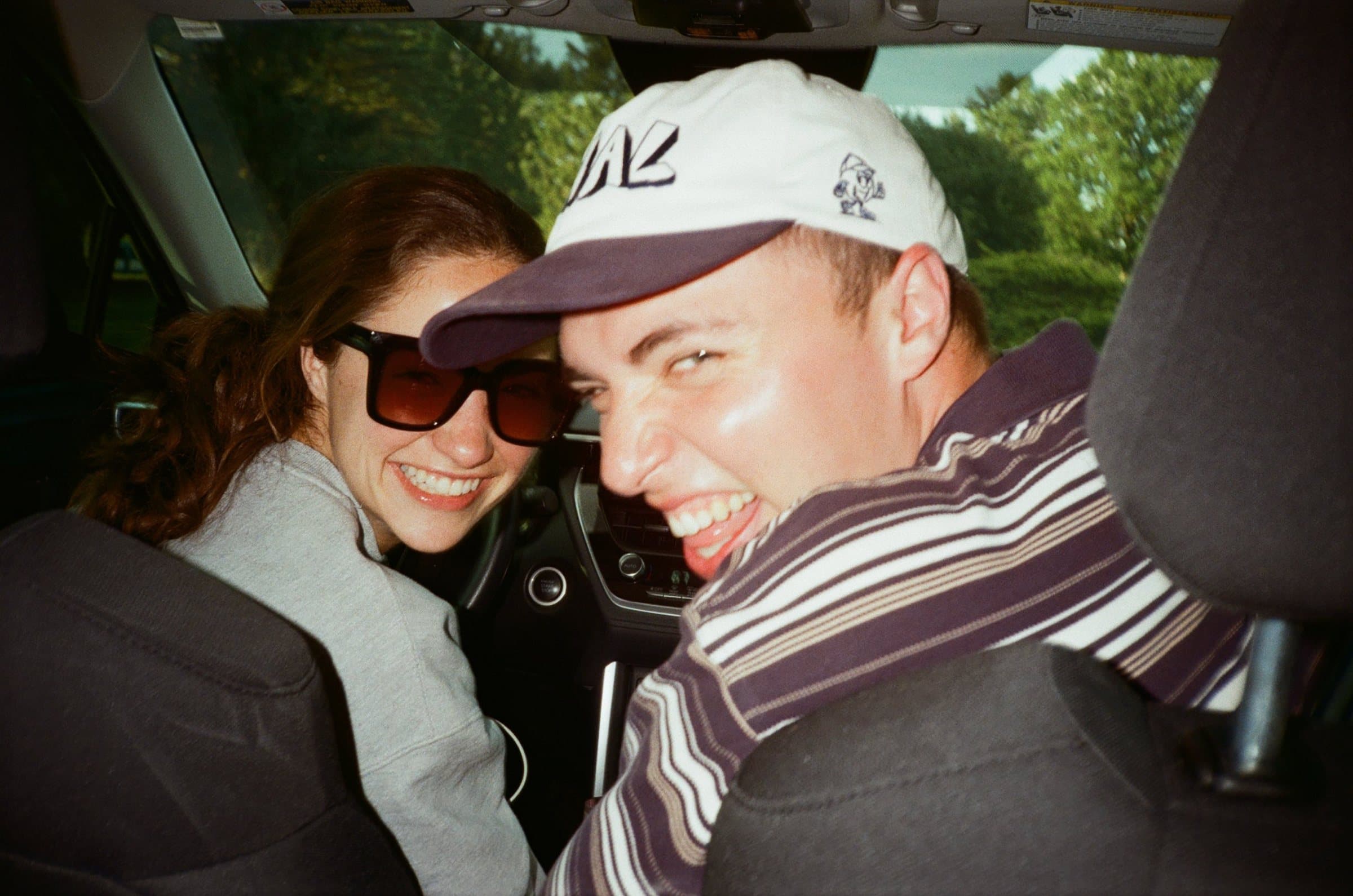 Two friends turning around from the front seats of a car, laughing